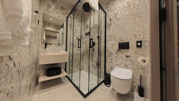Un baño moderno con ducha envuelta en vidrio, un lavabo blanco y un inodoro.