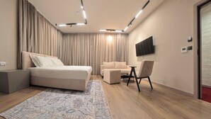 A modern bedroom with a bed, a sofa, a desk, and a TV. - Hotel Aquarius Adults Only (Dubrovnik)