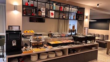 A buffet area with various food items, a coffee machine, and a beverage station.