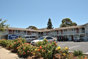 A motel with a sign reading "Budget Inn" and a parking lot with several cars. - Budget Inn (San Luis Obispo)