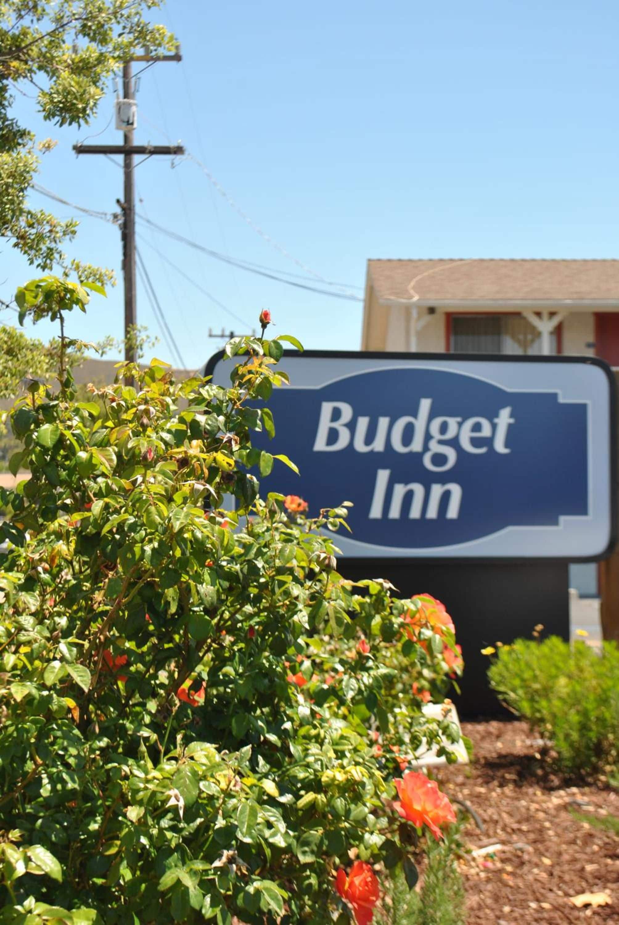 Indicador de Budget Inn amb una vista clara de l'entorn, incloent una línia elèctrica, vegetació i un edifici al fons.