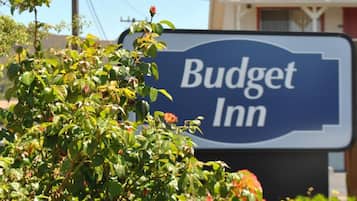 Indicador de Budget Inn amb una vista clara de l'entorn, incloent una línia elèctrica, vegetació i un edifici al fons.