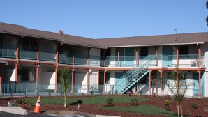 A multi-story hotel with balconies, a central staircase, and a well-maintained lawn. - Budget Inn (San Luis Obispo)