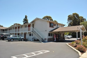 A motel with a two-story structure, a covered parking area, and a Coca-Cola sign. - Budget Inn (San Luis Obispo)