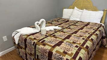 A bed with a patterned quilt, a wooden headboard, and a towel shaped like swans.