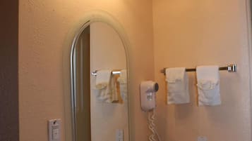 Une salle de bain équipée d’un lavabo, d’un miroir, d’un porte-serviettes et d’un sèche-cheveux.