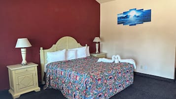 Una habitació d'hotel amb un llit, dues taules de nit amb làmpades, una obra d'art penjada a la paret i un sòl amb moqueta.