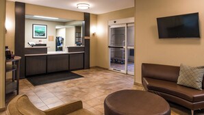 Eine Hotelhalle mit einer Rezeption, einer Sitzecke und einer Schiebetür zu einem Zimmer.