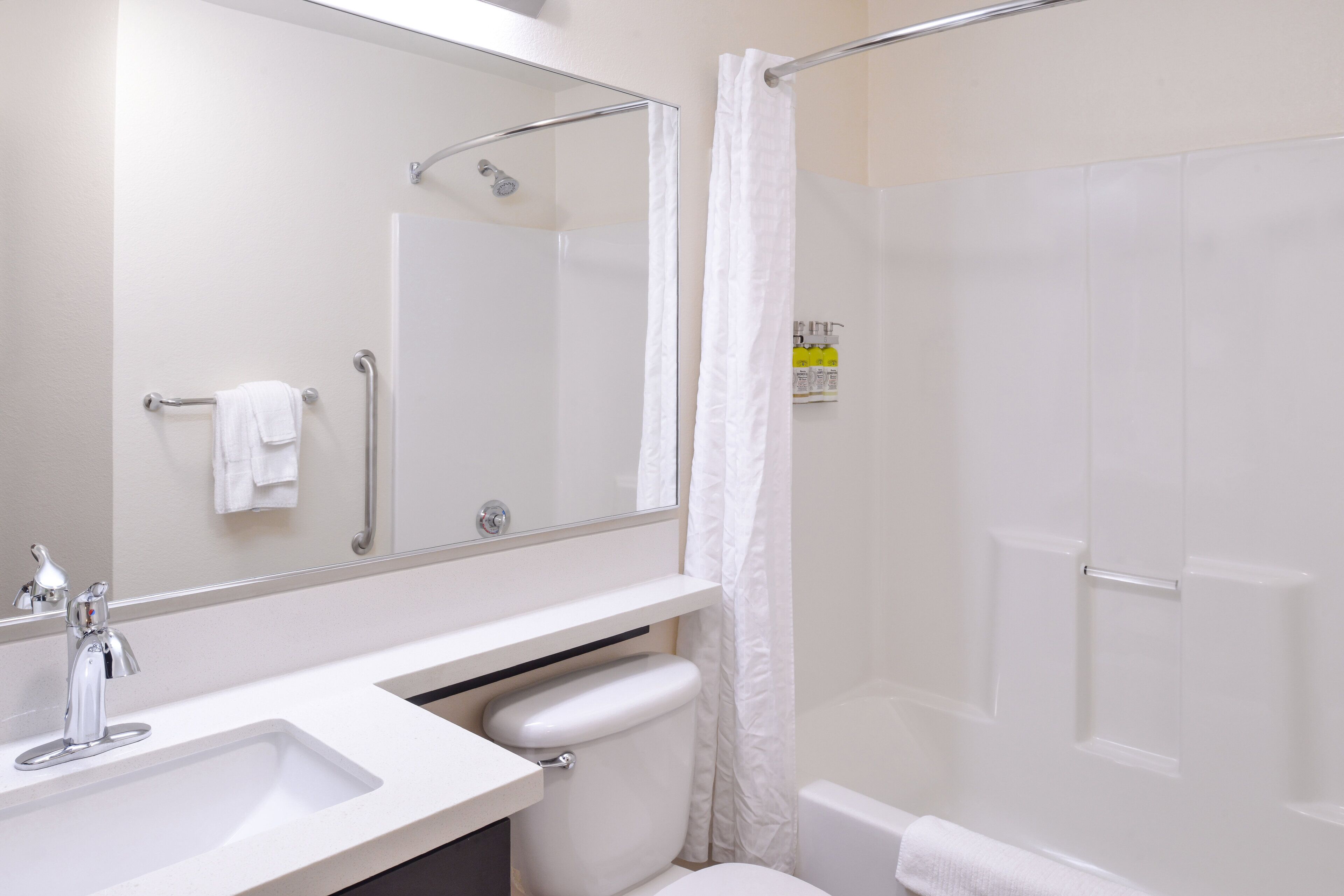 Een badkamer met een witte wastafel, een spiegel, een douche en een toilet.