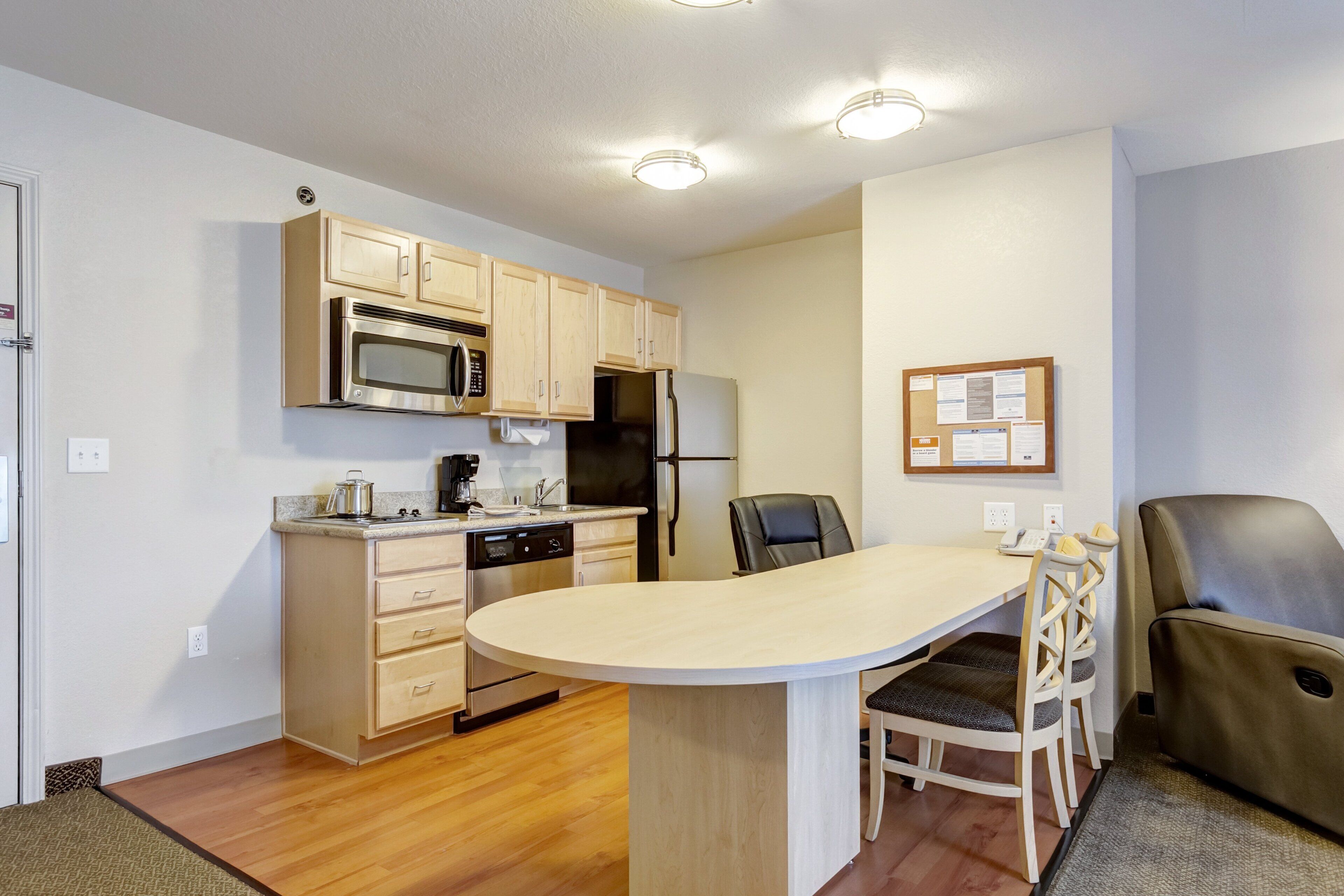 A compact kitchen with a microwave, stove, refrigerator, and a small dining area with a table and chairs.