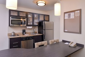 A modern kitchen with stainless steel appliances, a coffee maker, and a dining area with a table and chairs.