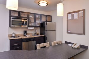 Una cocina moderna con electrodomésticos de acero inoxidable, cafetera y un comedor con mesa y sillas.