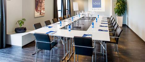 A conference room with a long table, chairs, and a projector screen displaying "idea hotel".