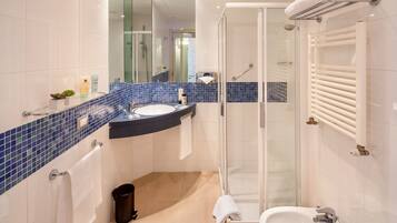 Un bagno moderno con doccia vetrata, lavabo bianco e mobile contenitore rivestito di piastrelle blu.