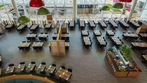 A spacious indoor dining area with multiple tables and chairs, large windows, and a central buffet station. - Leonardo Royal Resort Hotel Eilat (Eilat)
