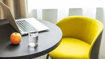 A laptop on a table with an apple and a glass of water.