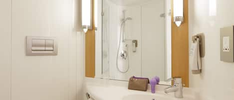 A modern bathroom with a white sink, a mirror, a shower, and a towel rack.