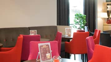 A hotel dining area with red upholstered chairs, a round table, and a menu stand.