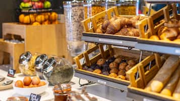 A breakfast buffet with various food items including muffins, croissants, and hard-boiled eggs.