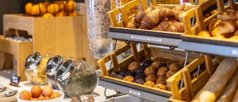 A breakfast buffet with various food items including muffins, croissants, and hard-boiled eggs.
