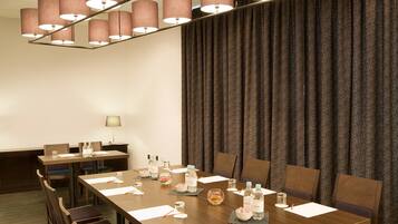 A conference room with a long table, chairs, and a backdrop of curtains.