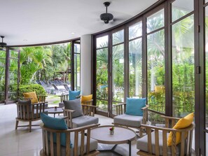 A spacious indoor area with large windows, wooden furniture, and a view of a lush garden. - ibis Phuket Patong (Patong)