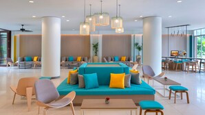 Un vestíbulo moderno con un sofá color turquesa, sillas de madera e iluminación colgante.