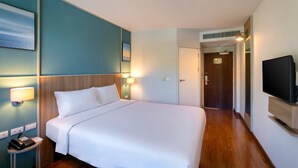 Habitación de hotel con una cama grande, lámparas de noche, un televisor de pantalla plana y una puerta que da a otra habitación.