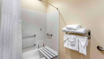 A bathroom with a shower, a bathtub, and a towel rack with folded towels.