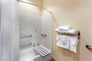 A bathroom with a shower, a bathtub, and a towel rack with folded towels.