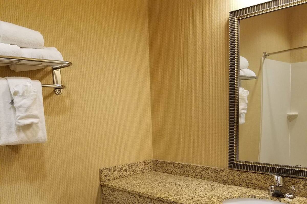 A bathroom with a toilet, sink, and mirror.