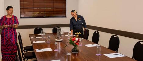 A conference room with a long table, chairs, name tags, and a window with blinds.