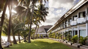 A hotel with a modern design, featuring a long building with balconies and a well-maintained lawn with palm trees. - Novotel Suva Lami Bay (Suva)
