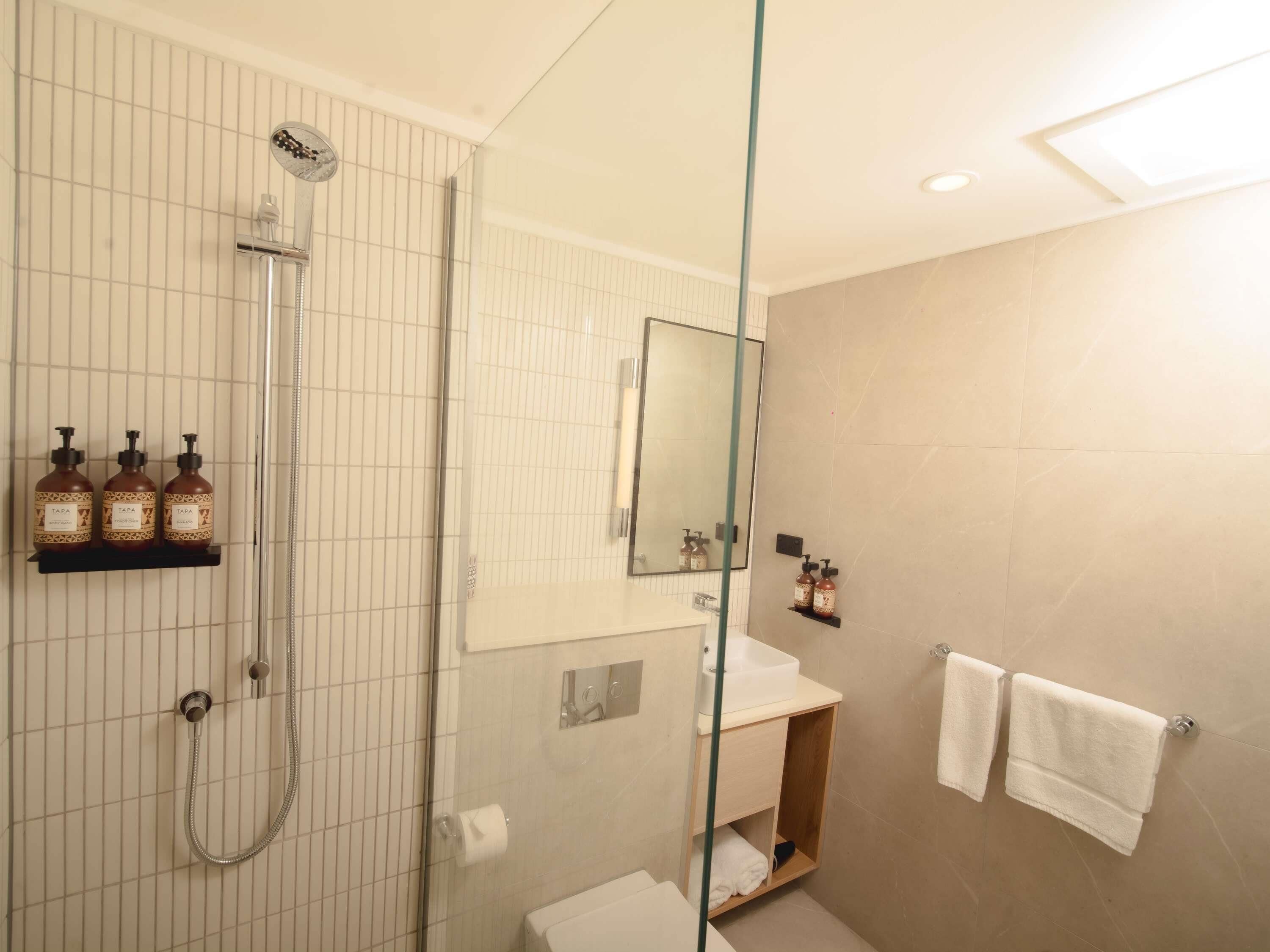 A modern bathroom with a glass shower enclosure, a vanity with a mirror, and a towel rack.