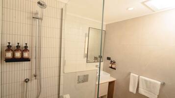 A modern bathroom with a glass shower enclosure, a vanity with a mirror, and a towel rack.