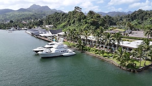 A waterfront property with a large yacht docked, surrounded by lush greenery and a mountain backdrop. - Novotel Suva Lami Bay (Suva)
