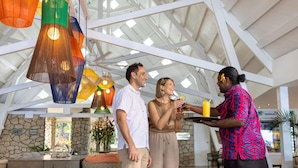 A spacious indoor area with a high ceiling, stone walls, and a dining area with wicker furniture. - Novotel Suva Lami Bay (Suva)