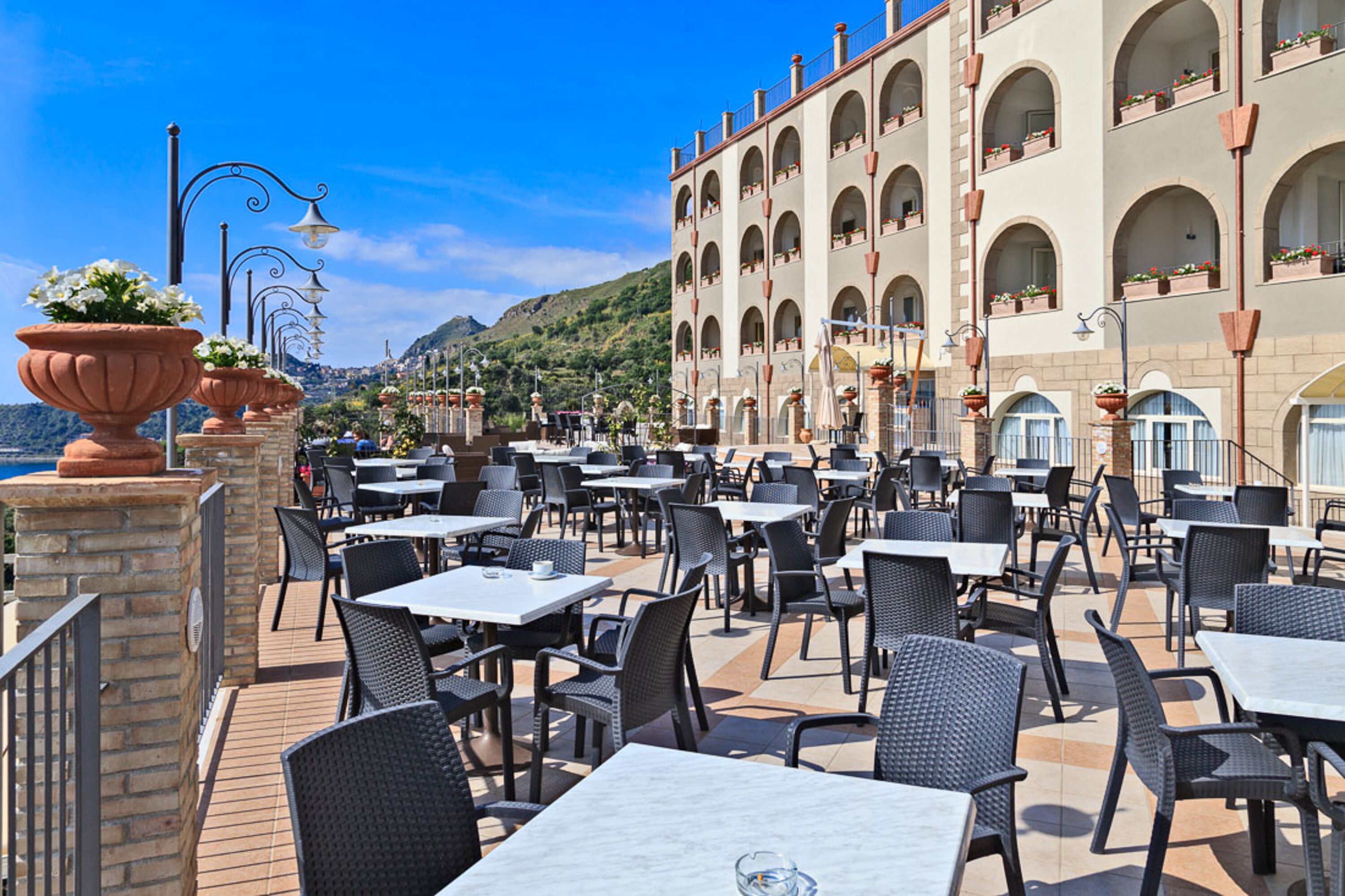 An outdoor cafe with tables and chairs, overlooking a scenic mountain view.