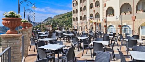 An outdoor cafe with tables and chairs, overlooking a scenic mountain view.