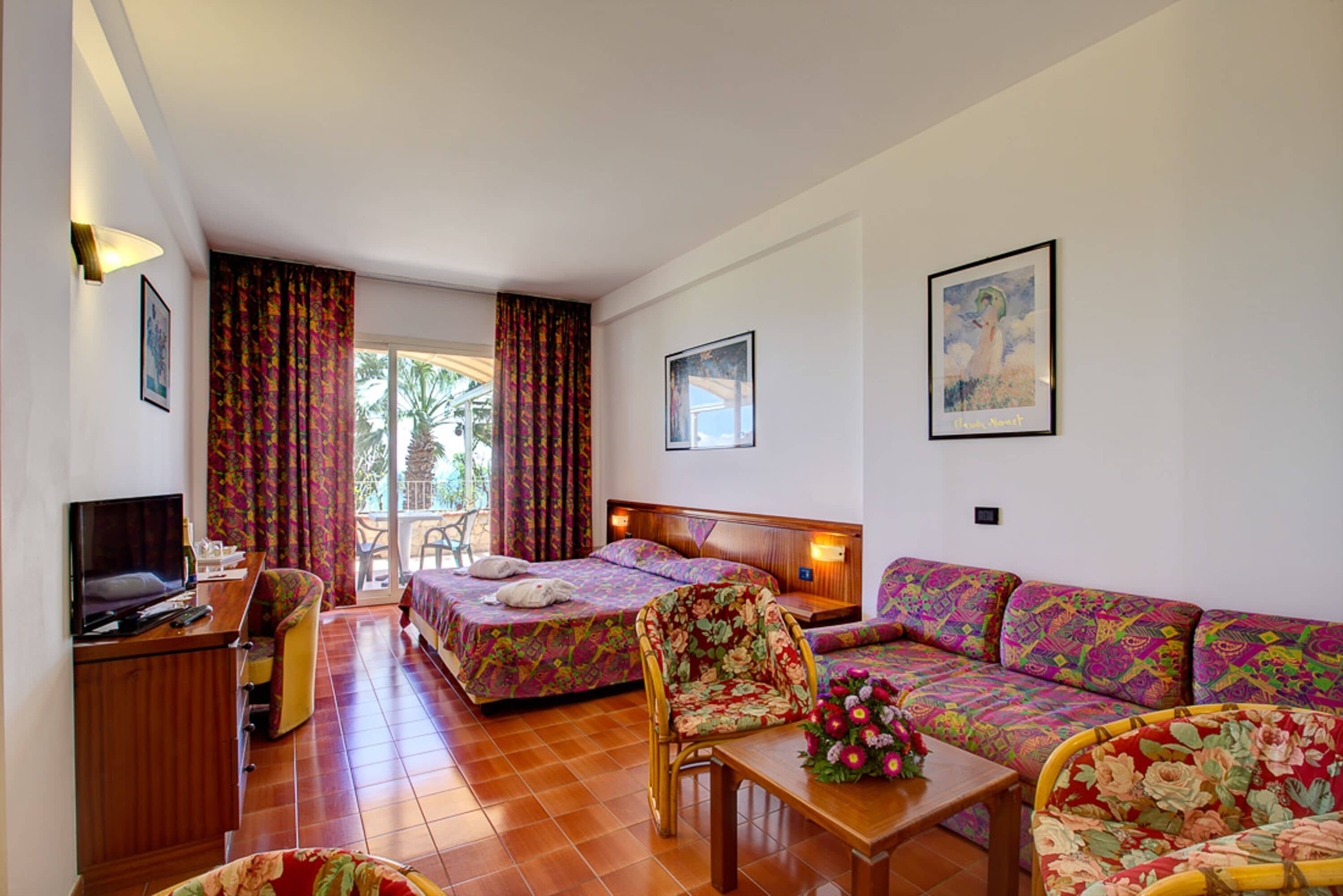 Habitación de hotel con dos camas, un sofá, un televisor y un escritorio.
