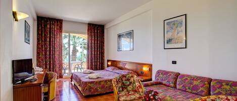 Habitación de hotel con dos camas, un sofá, un televisor y un escritorio.
