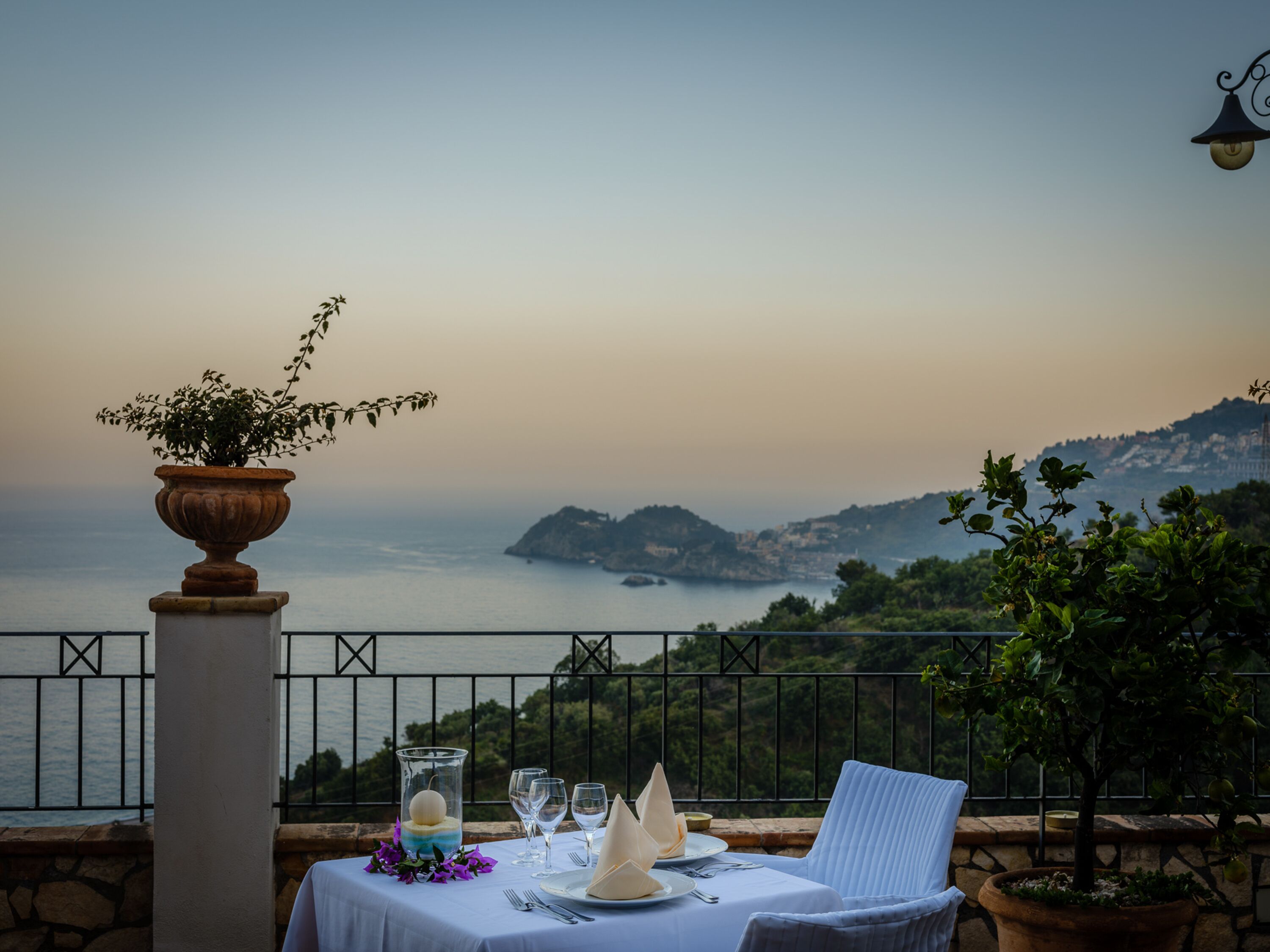 Mesa para dos con vista al mar y colinas al fondo.