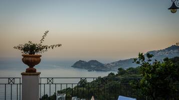 A table set for two with a view of the sea and hills in the background.