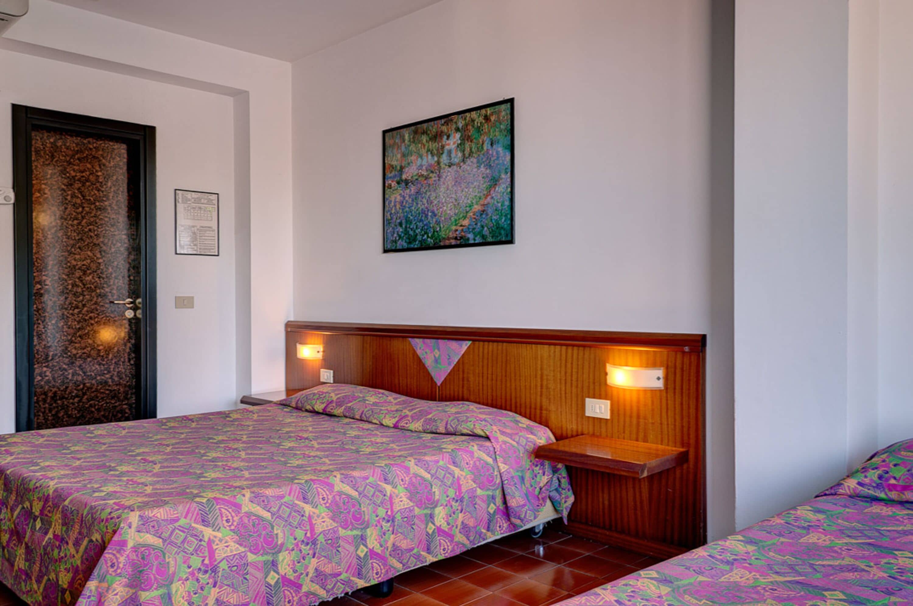 Una habitación de hotel con dos camas, un cabecero de madera, una puerta decorativa y una obra de arte enmarcada en la pared.