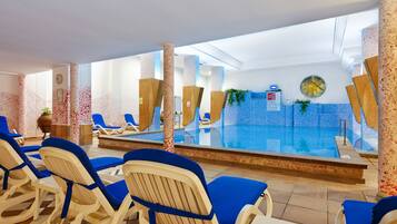Un espace piscine avec des chaises longues bleues et un comptoir d’accueil.