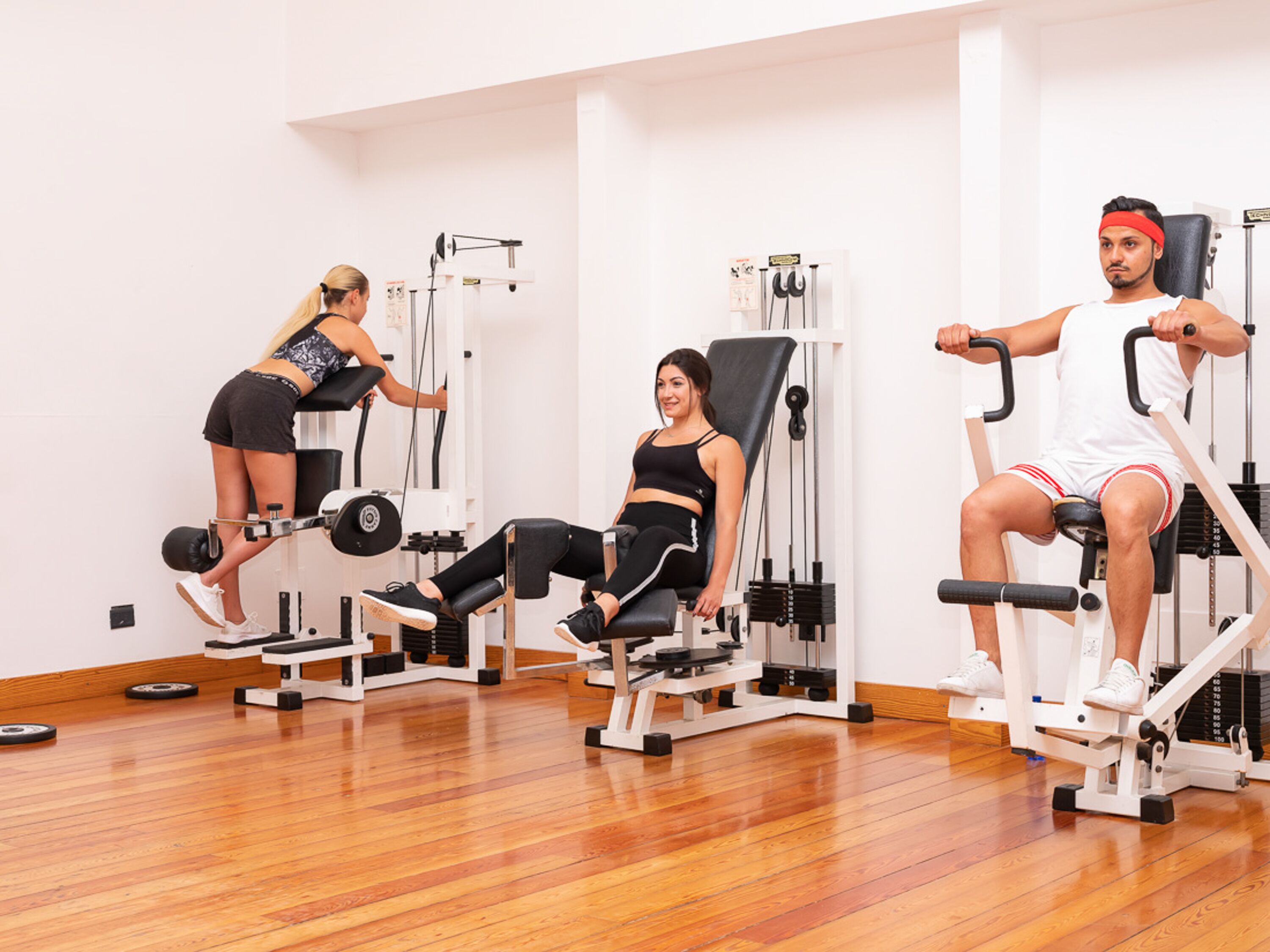 Una palestra con tre persone che utilizzano macchinari per l'allenamento.