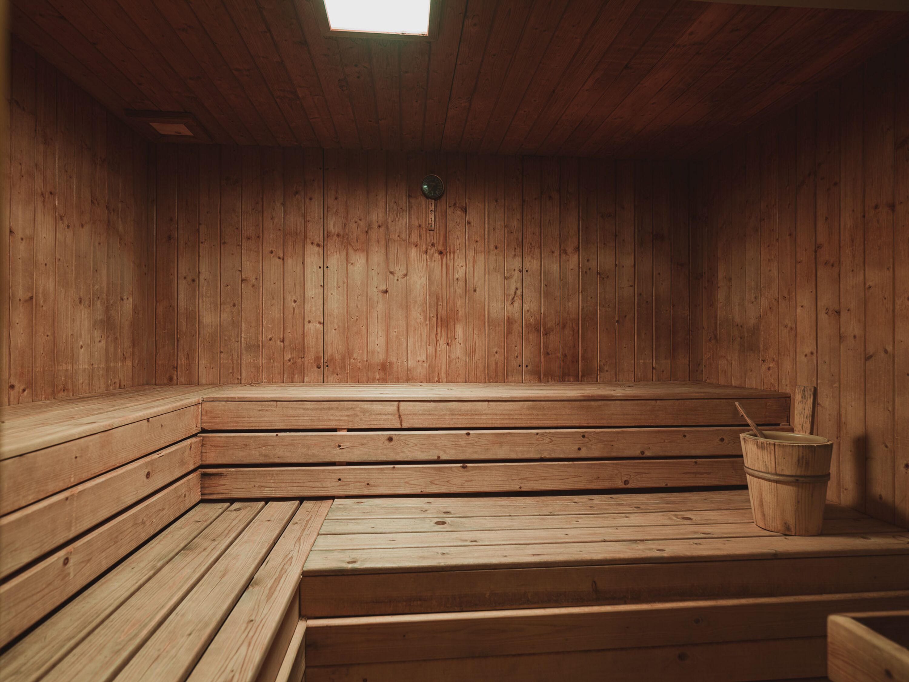 A wooden sauna with benches and a bucket.