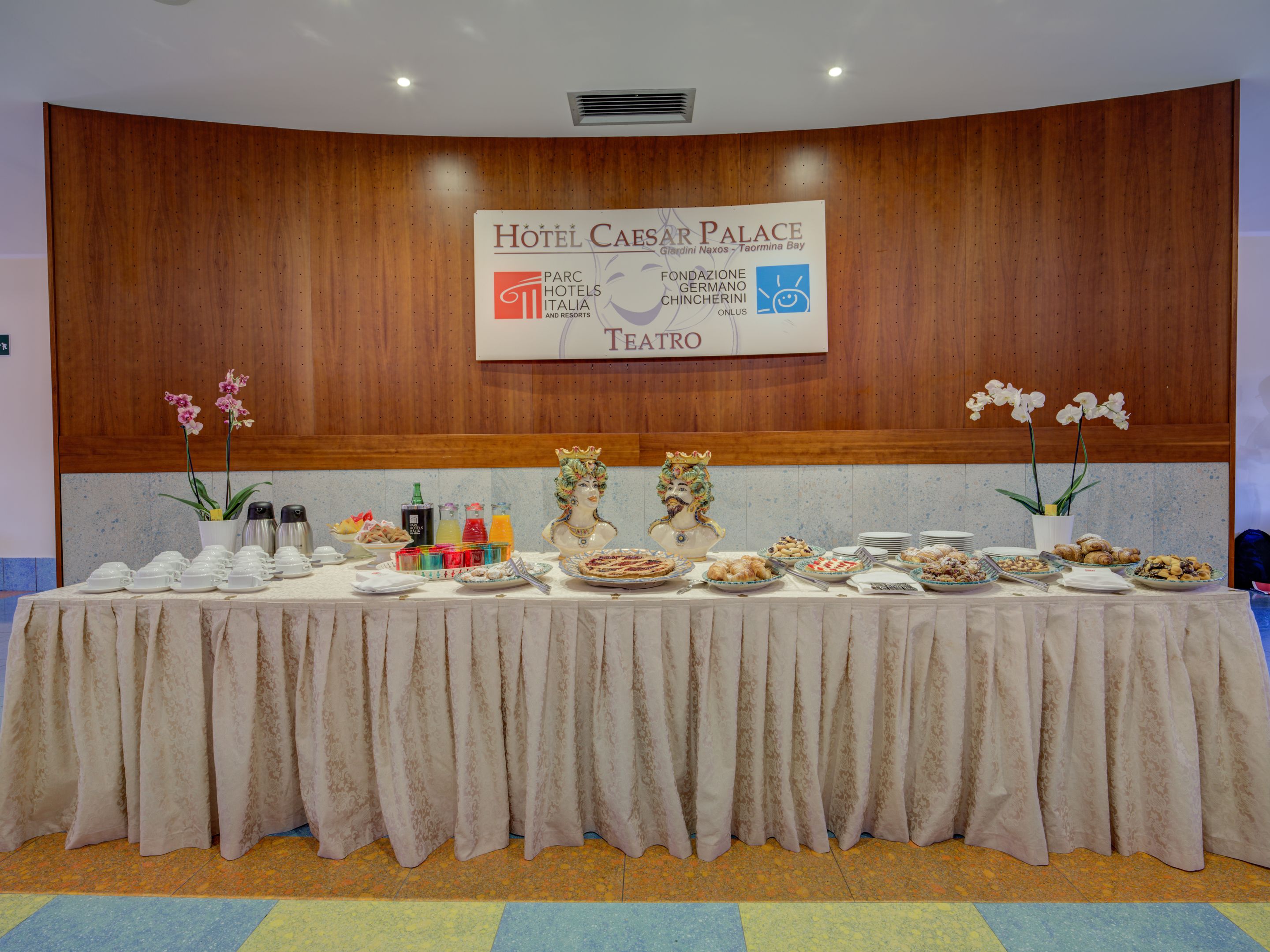 A banquet table set up in a hotel lobby with a sign reading "Hotel Cesar Palace" and "Teatro".
