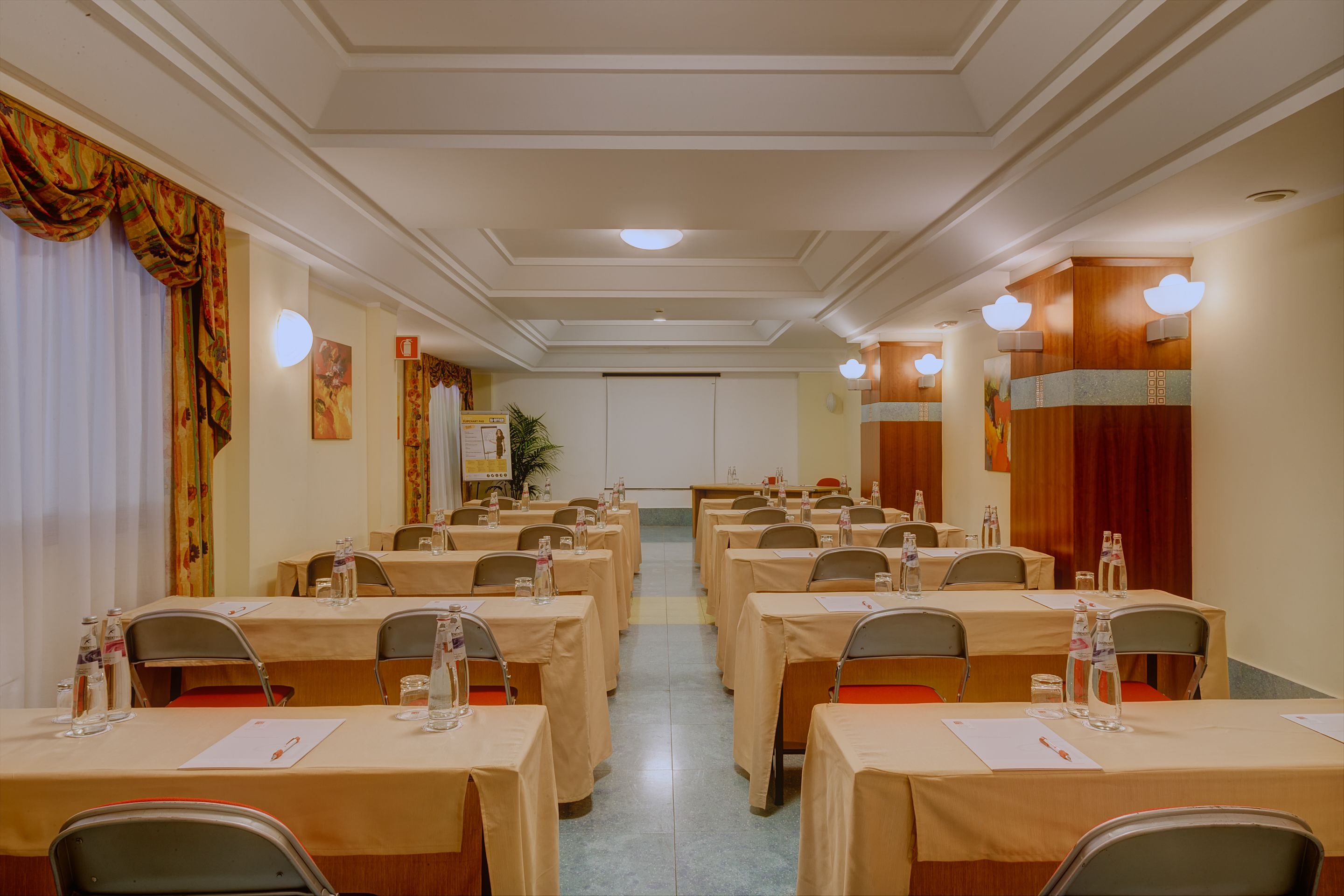 Une salle de conférence équipée de plusieurs tables, de chaises et de bouteilles d’eau.