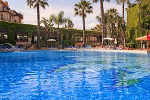 Una piscina con sillas de descanso y palmeras.